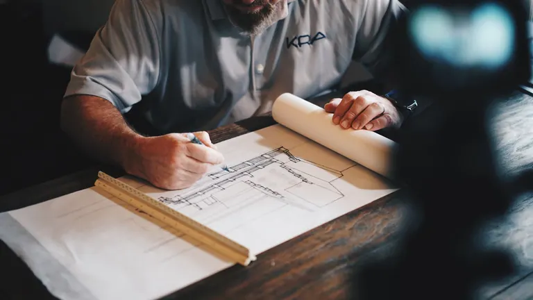 Engineer marking up construction drawings at a desk