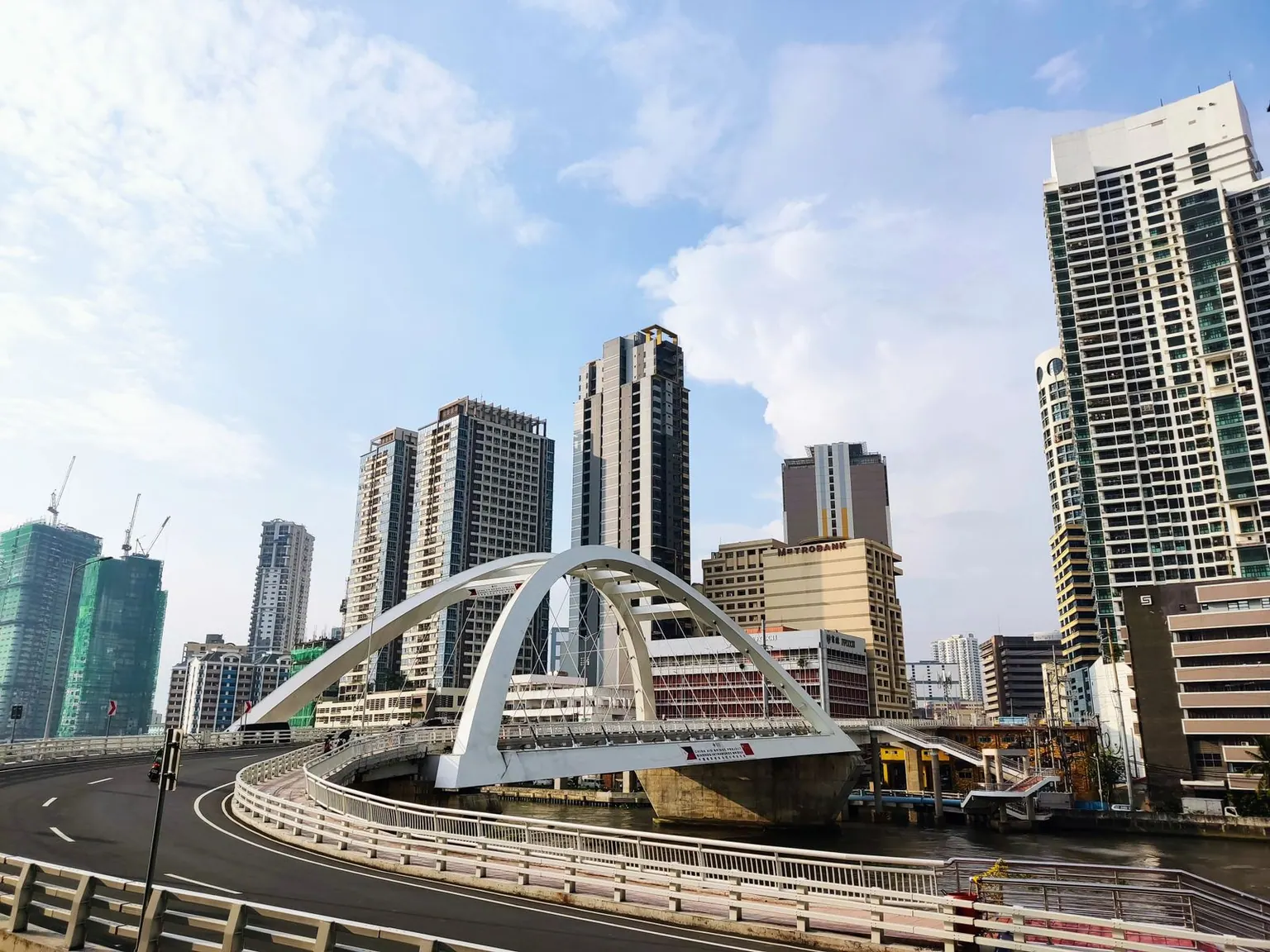 A contemporary bridge amid skyscrapers in Manila, showcasing urban development.