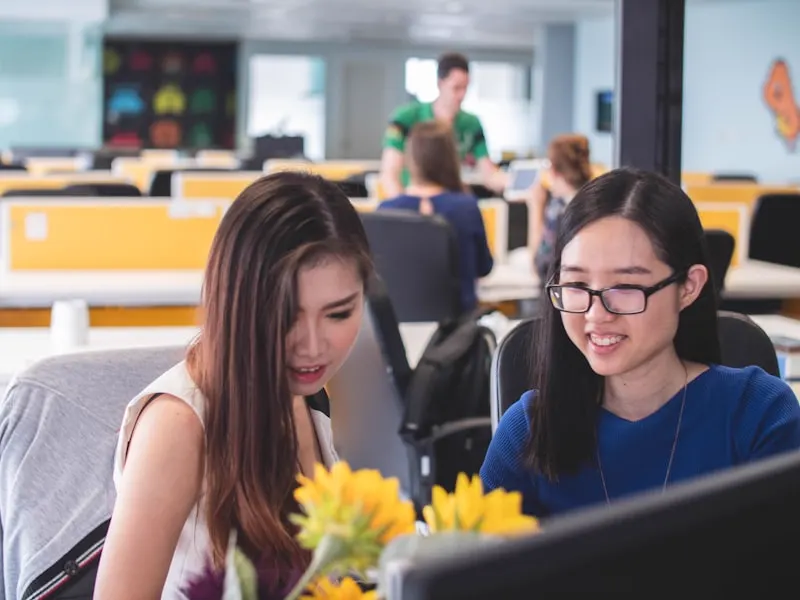 Two colleagues smiling at a shared monitor